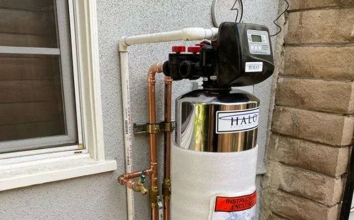 Water treatment tank installed outdoors with a service bypass